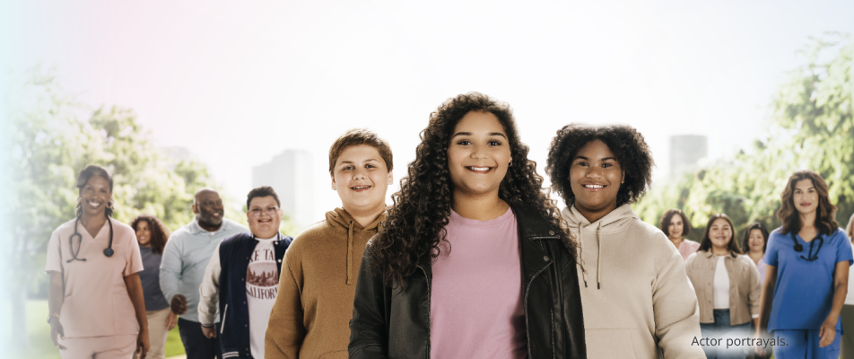 A group of adolescents with a variety of skin tones and gender presentations smiling. Actor portrayals.