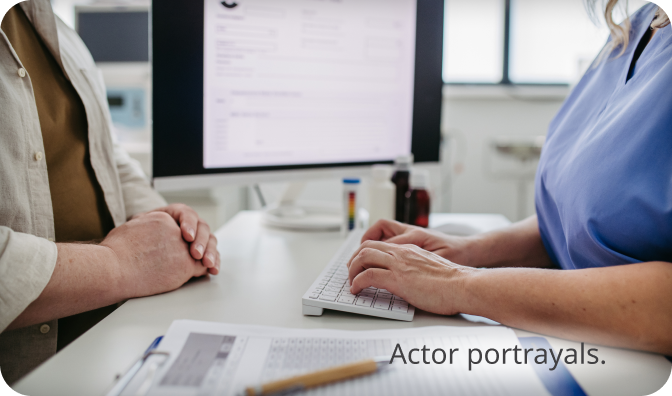 A light skin toned, feminine-presenting person sitting at their kitchen table and looking at a laptop. Actor portrayal.