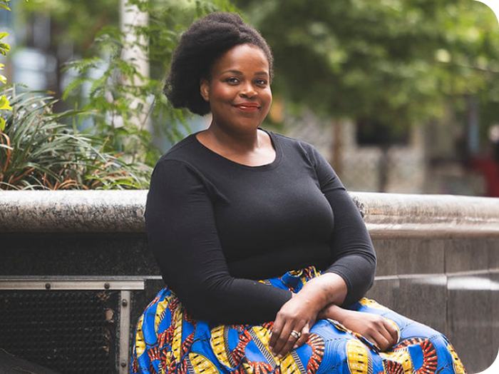 Keytsiia, dark-skinned and feminine-presenting, is seated outdoors, smiling. Keytsiia is a real person taking Wegovy since 2023.