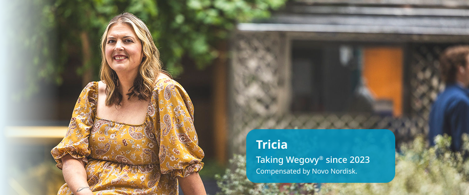 Tricia, light-skinned and feminine-presenting, is seated at a park, smiling. Tricia is a real person taking Wegovy since 2023.