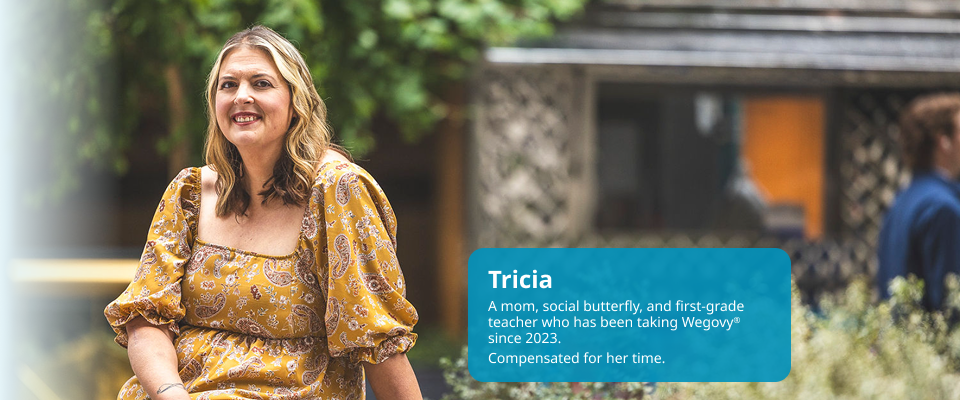 Tricia, light-skinned and feminine-presenting, is seated at a park, smiling. Tricia is a real person taking Wegovy since 2023.