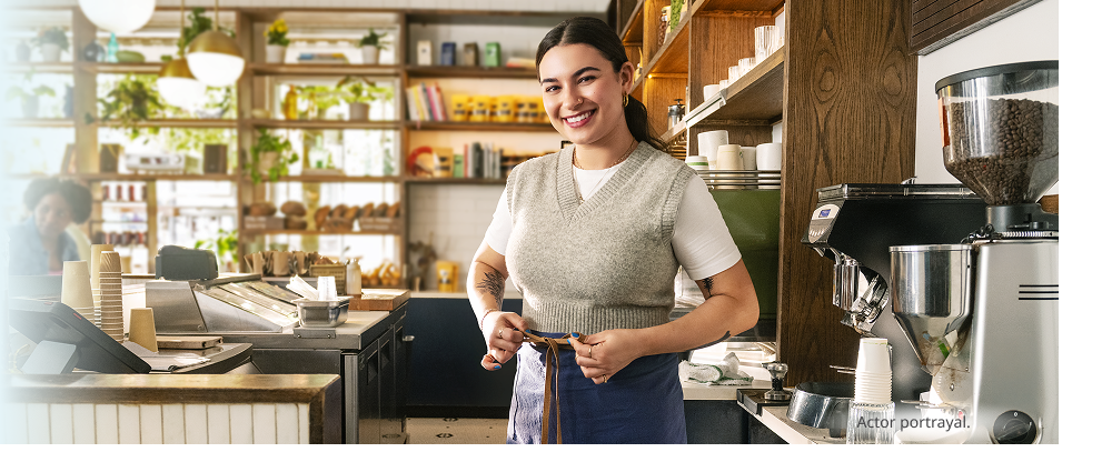 A person, medium-dark skin toned and feminine-presenting in their thirties, standing confidently in a salon. Actor portrayals.