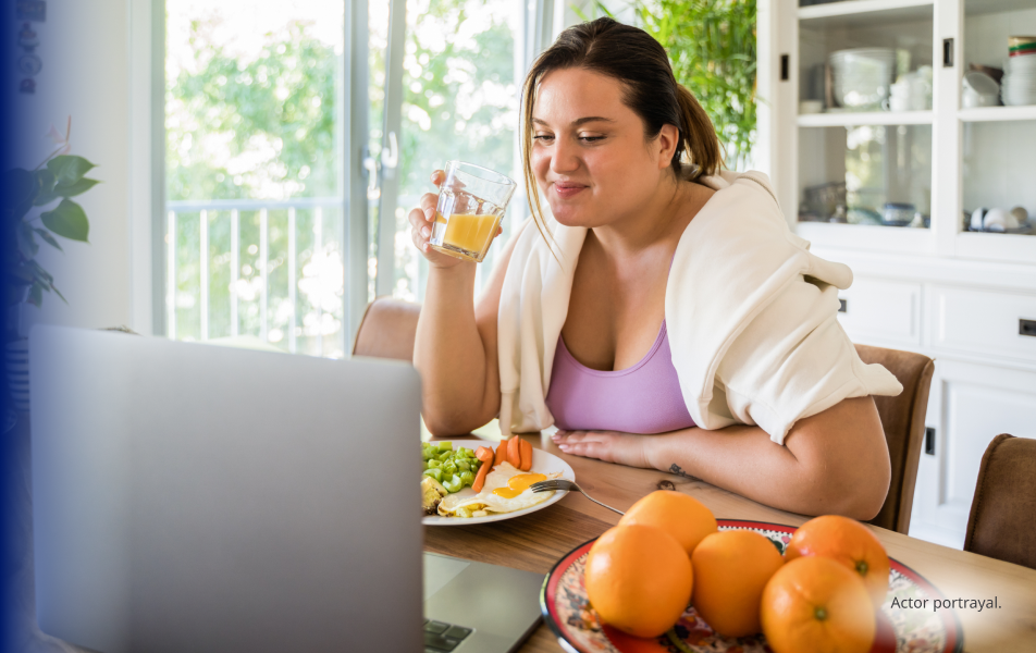 A light skin toned, feminine-presenting person in their thirties enjoying an orange juice and veggies. Actor portrayal.